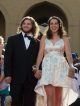 A young man and young woman walk the red carpet to the formal.