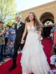 A young man and young woman walk the red carpet to the formal.