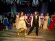 A young man and young woman dance on the dance floor while everyone watches.