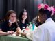 A young woman gets her nails painted.