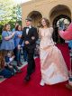 A young man and young woman walk the red carpet to the formal.