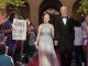 A young man and young woman walk the red carpet to the formal.