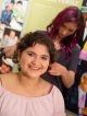 A girl smiles while getting her hair styled.