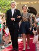 A young man and woman walk the red carpet in their formal wear.