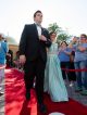 A young man and woman walk the red carpet whlie onlookers cheer.