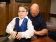 Boy getting help putting on his tuxedo.