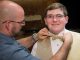 A teen getting his bowtie tied.