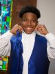 A boy getting dressed in his tuxedo for prom.