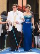 A young man and his date walking the blue carpet for the prom.