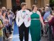 A young couple walks the blue carpet in their prom attire.