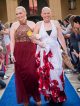 Two young ladies in their prom gowns walk the blue carpet.