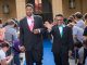 Two young men walk the blue carpet in their tuxedos.