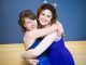 Two girls in prom dresses hugging
