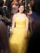 Girl in yellow prom dress walking the red carpet into the event