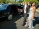 Prom couple posing by limosine