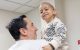 St. Jude patient Emmanuel, wearing a white sweater, smiles while on his dad's arms.