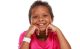 St. Jude patient Kinsley sits cross-legged on the floor, smiling as she rests her face in her hands