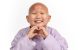 St. Jude patient Misheel sits on the floor, forming a heart with her hands.