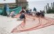 Researchers spread out a cannon net on the beach.