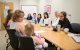 A mother and child participating in the clinic sit at table and talk to experts in areas of research and treatment.