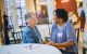 Janice and Sonia sit at a table and talk.