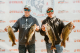 Two Dick Hiley Bass Classic participants hold up their catches and smile at weigh-in. 