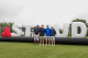 Golfers stand by large inflatable letters spelling 