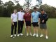 Golfers posing with their golf clubs and smiling
