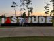 Four people standing in front of a large "I love St. Jude" sign