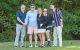 St. Jude Peninsula Golf Tournament attendees pose on the green holding golf clubs. 