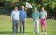 Golfers pose on the green beside a St. Jude golf flag. 