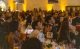 In a warmly lit ballroom, attendees listen to a speaker at St. Jude Miracles on the Bay. 
