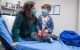 St. Jude patient Griffin and his mother wear masks while sitting on a bed in a hospital room.