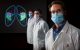 Three researchers in lab coats and masks stand in front of a lung illustration.