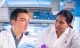 Two researchers wearing labcoats talking about research in a lab.