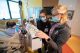 Two nurses with masks checking vitals on a patient.