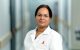 Researcher in lab coat smiling at camera.