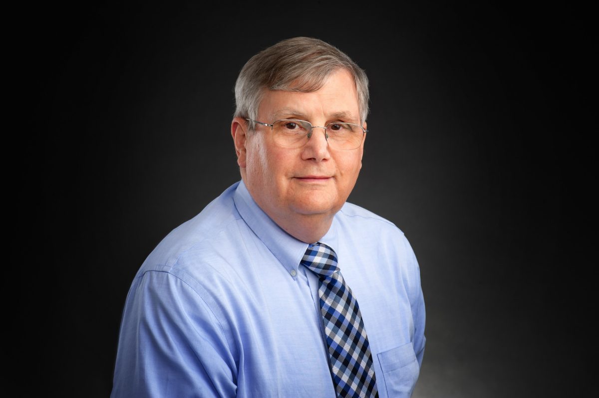 studio portrait of Dr. Wayne Furman wearing a blue shirt with a necktie 