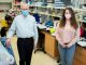 Two researchers are standing in a lab wearing masks and looking at the camera. 