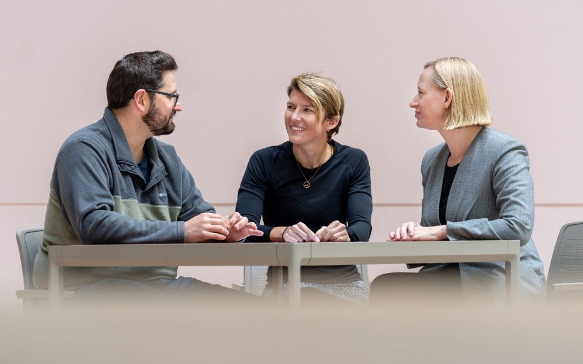 Three St. Jude researchers sitting at a table and having a conversation.