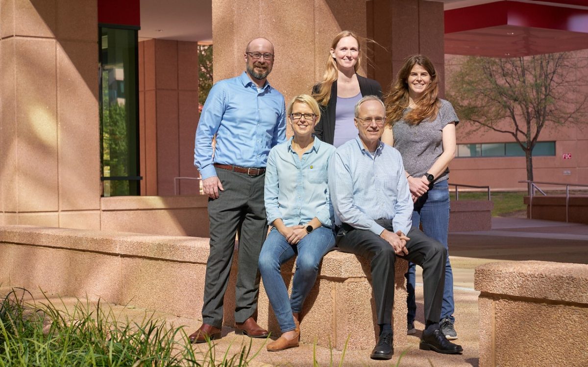 five scientists sitting outdoors 