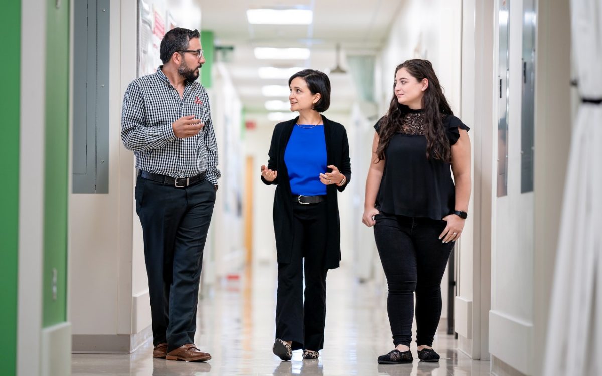 Three St. Jude scientists walking in a hallway near their laboratory. 