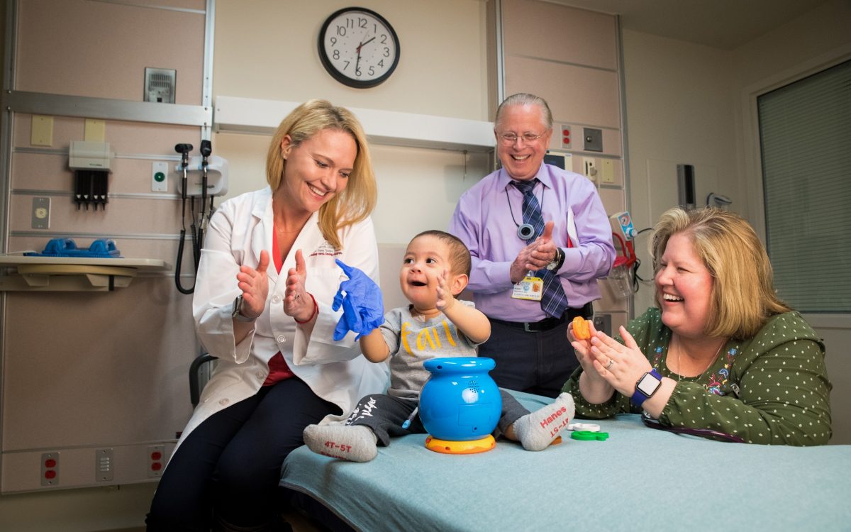 Ewelina Mamcarz, MD, celebrates with baby patient. Interpreter Marc Friedman and nurse practitioner Katie Birdsell are also pictured. 