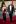 St. Jude patient in tuxedo walks with young woman in a maroon dress on red carpet at St. Jude Teen Formal.