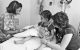 Patient sits up on the bed with parent behind her providing comfort