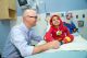 St. Jude physician Dr. Triplett talking to young male patient who is sitting on hospital bed