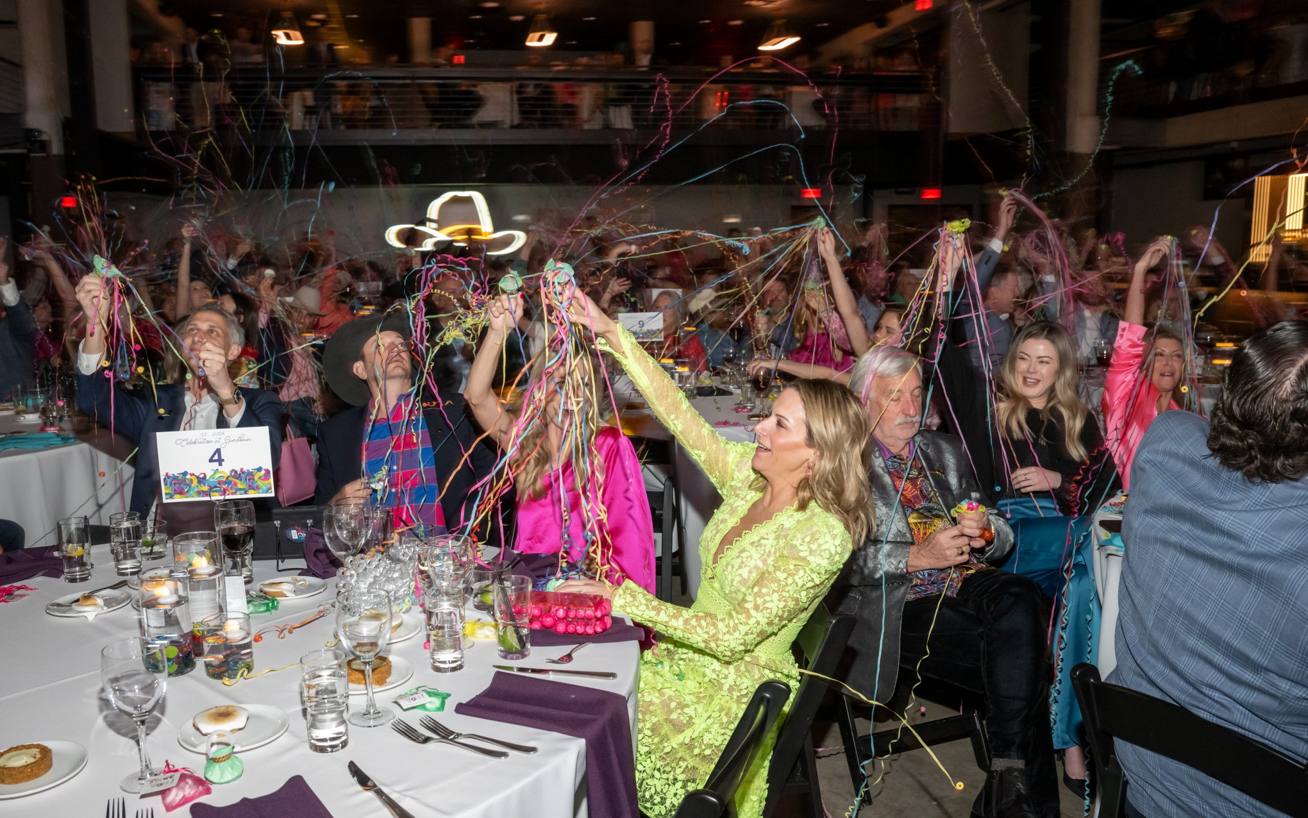 St. Jude Celebration at Sundown attendees cheer and raise arms amidst streamers. 