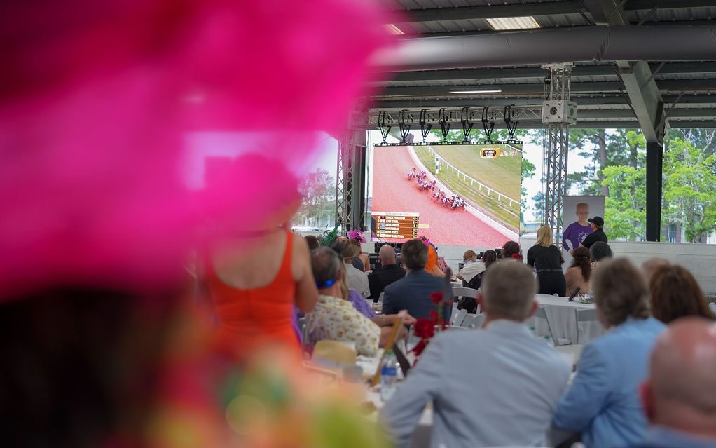 St. Jude A Day at the Derby attendees watch the Kentucky Derby on a large screen. 