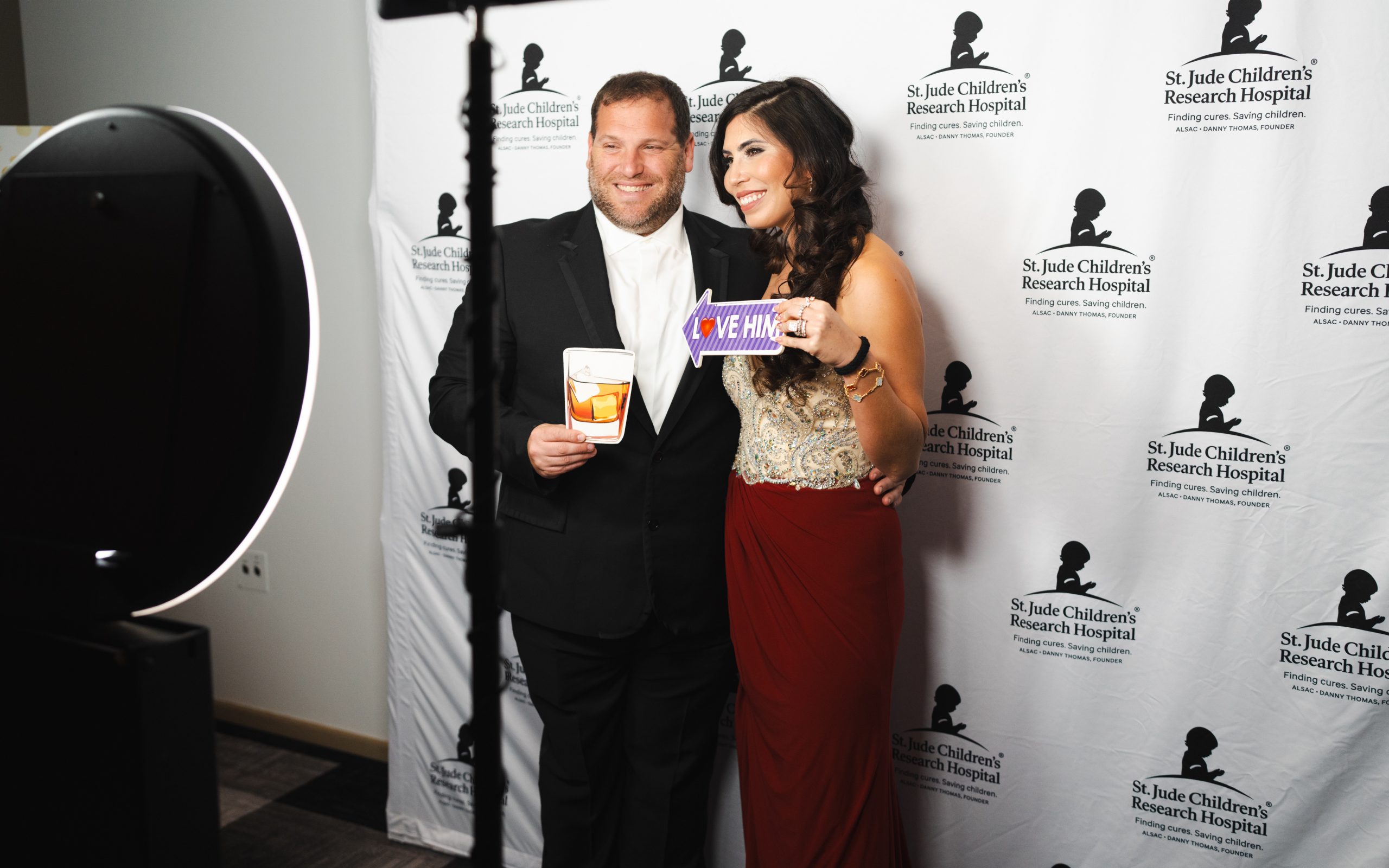 Evening of Hope attendees pose in front of a wall emblazoned with the St. Jude logo. 
