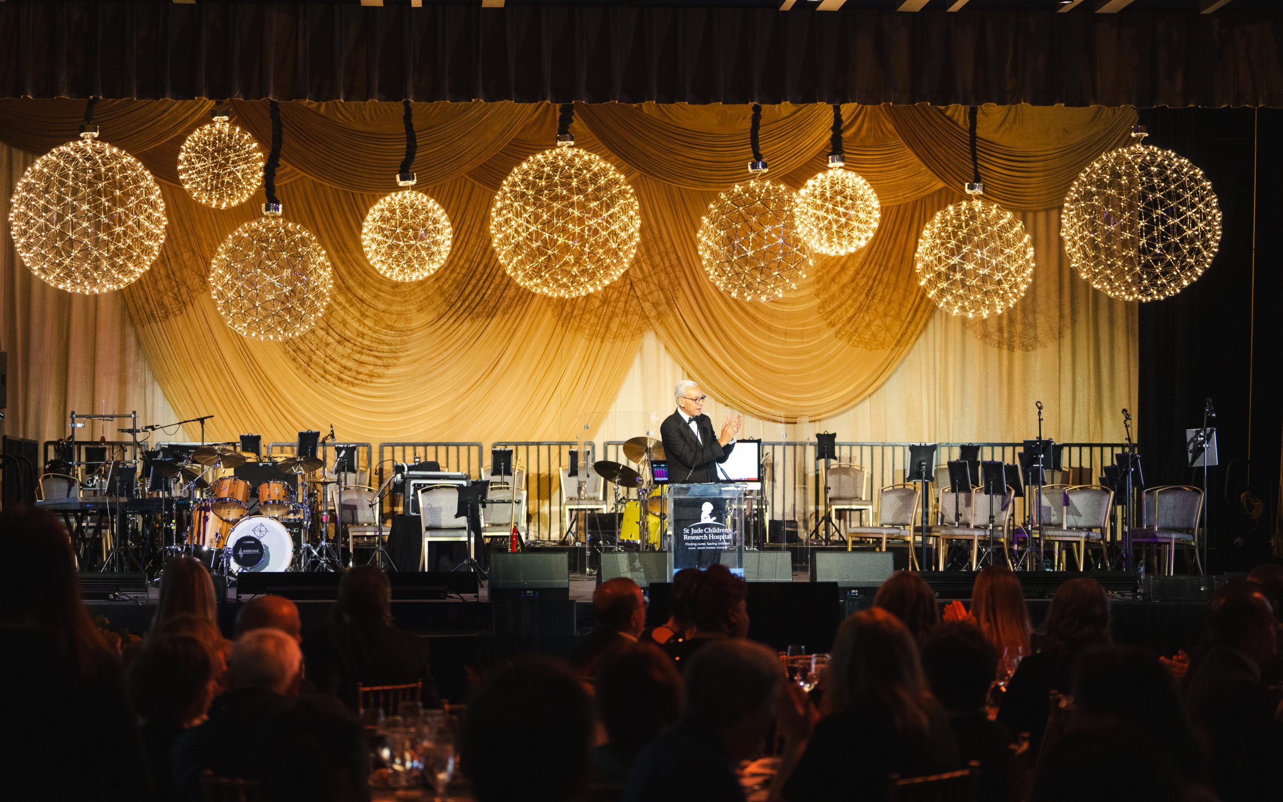 A speaker addresses the audience from a ballroom stage at the St. Jude Evening of Hope Gala in Los Angeles. 